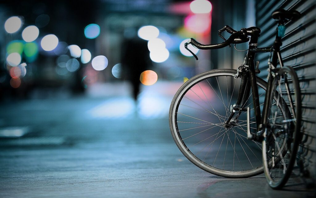 A bicycle leaned against a wall on a nearly-empty street.