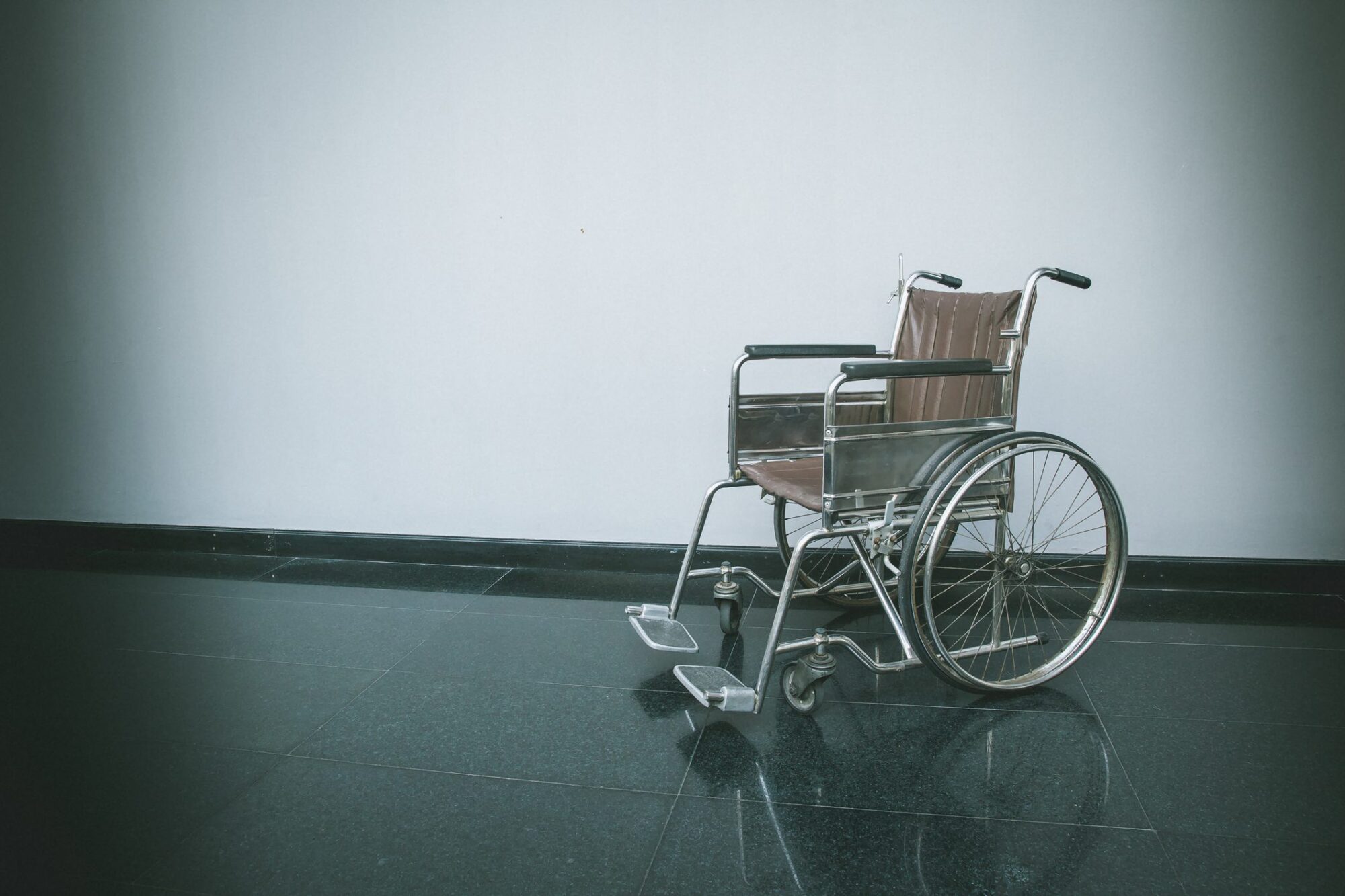 Empty Wheelchair Parked In Hospital Walk Way. Empty Wheelchair Standing Alone In A Patient Room